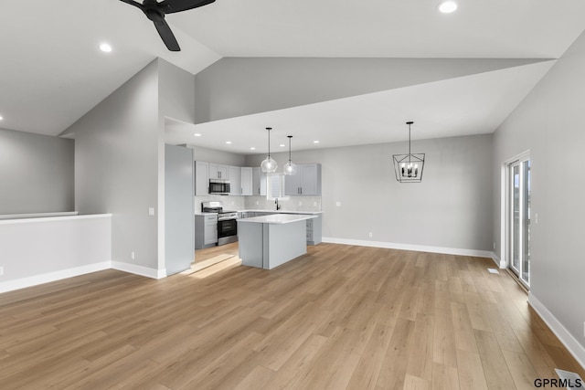 kitchen featuring gray cabinets, light wood-type flooring, decorative light fixtures, a kitchen island, and stainless steel appliances