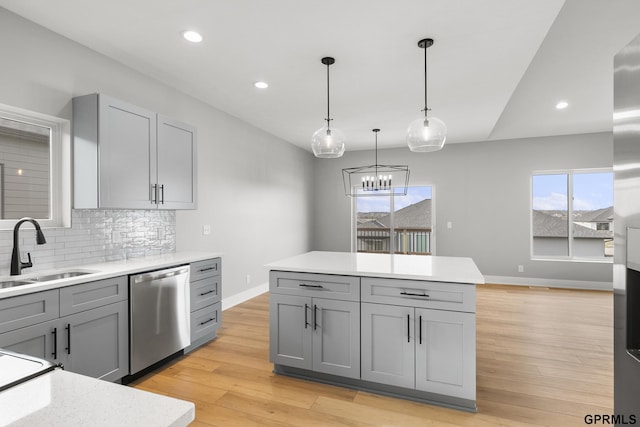 kitchen featuring gray cabinetry, a wealth of natural light, dishwasher, and sink