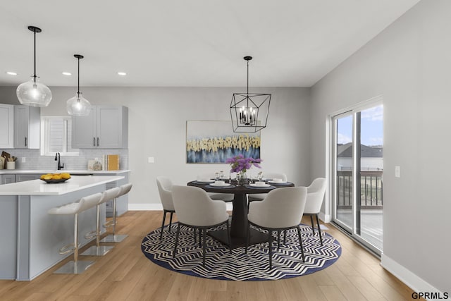 dining room with a notable chandelier, light wood-type flooring, and sink