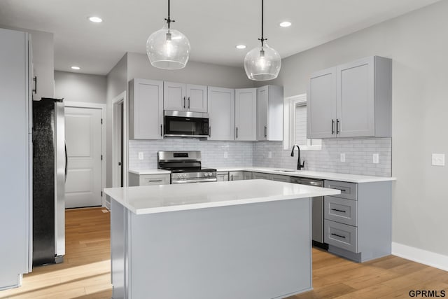 kitchen featuring pendant lighting, a center island, stainless steel appliances, and light hardwood / wood-style flooring