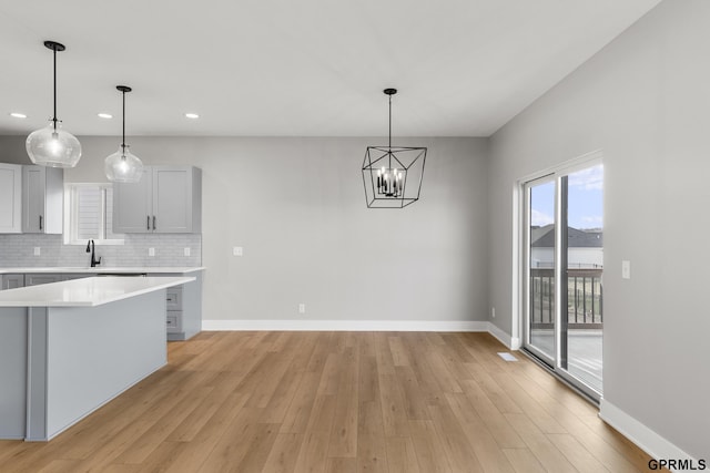 kitchen featuring pendant lighting, light hardwood / wood-style floors, sink, and tasteful backsplash