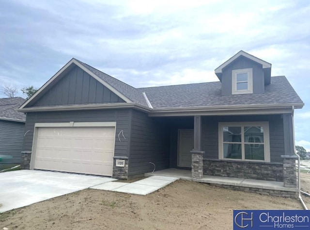 view of front facade with stone siding, an attached garage, board and batten siding, driveway, and a porch