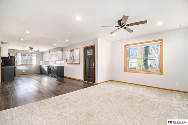 unfurnished living room featuring ceiling fan, dark hardwood / wood-style flooring, and sink