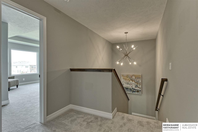 staircase with carpet floors, a textured ceiling, and a chandelier