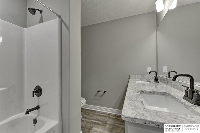 full bathroom featuring vanity, bathing tub / shower combination, hardwood / wood-style flooring, toilet, and a textured ceiling