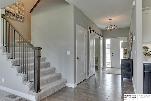 entryway with a barn door and dark wood-type flooring