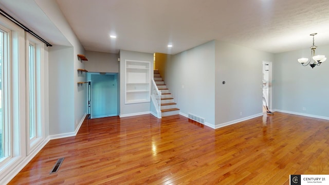 unfurnished living room featuring hardwood / wood-style floors and a chandelier