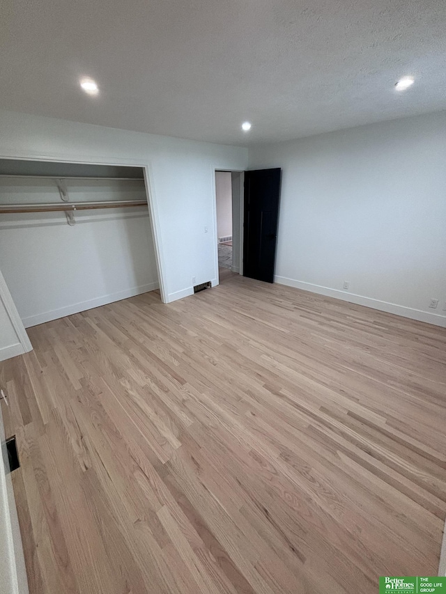 unfurnished bedroom featuring a closet, a textured ceiling, and light hardwood / wood-style flooring