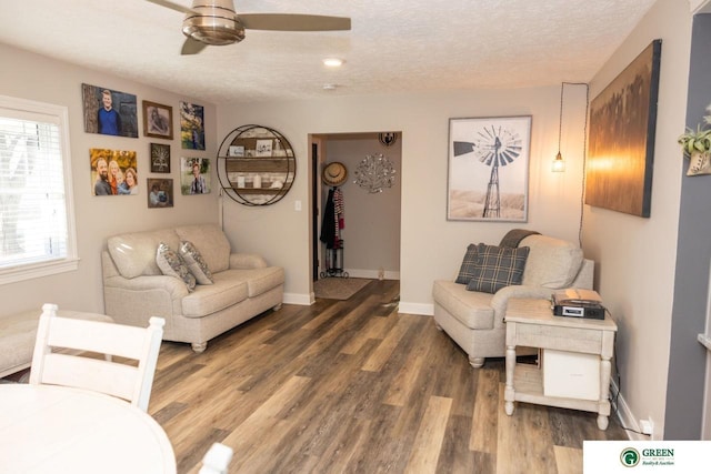 living room with a textured ceiling, dark hardwood / wood-style flooring, and ceiling fan