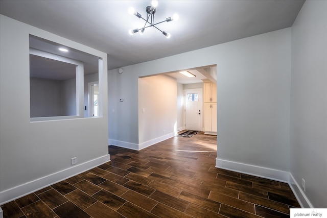 spare room with dark hardwood / wood-style flooring and a chandelier