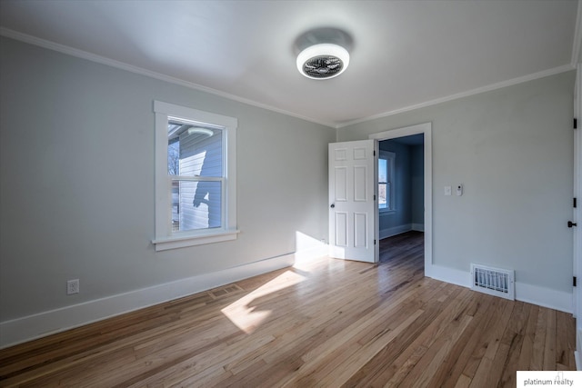 spare room with light wood-type flooring and crown molding