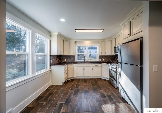 kitchen with dark hardwood / wood-style floors, decorative backsplash, sink, and appliances with stainless steel finishes