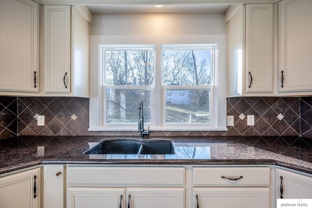 kitchen with white cabinets, sink, and dark stone counters