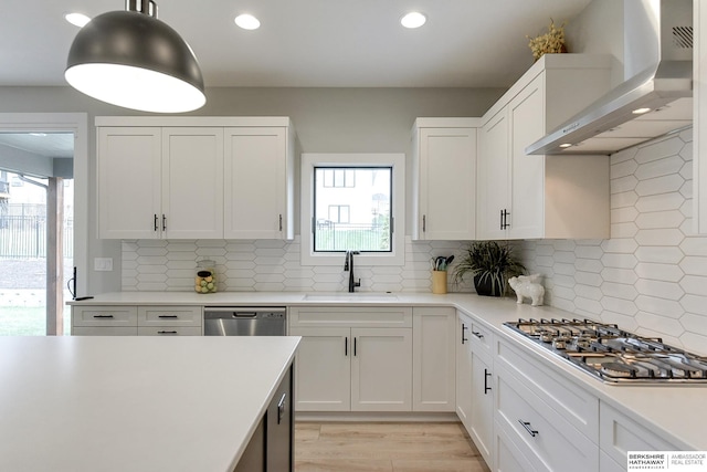 kitchen featuring white cabinets, wall chimney exhaust hood, decorative backsplash, and sink