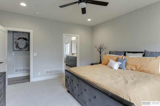 bedroom with ensuite bathroom, ceiling fan, and light carpet