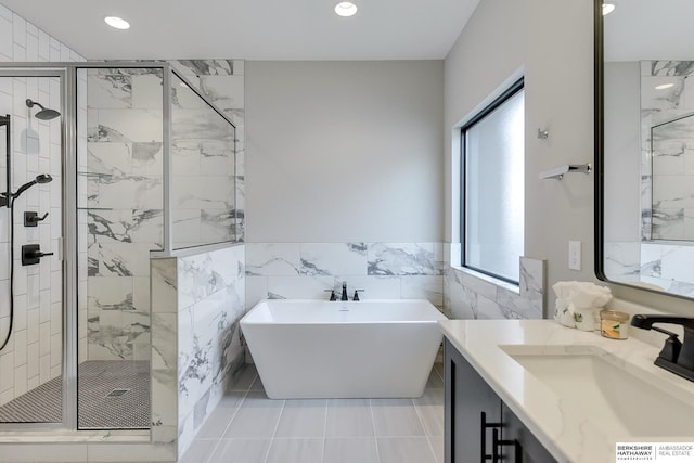 bathroom featuring plus walk in shower, vanity, tile walls, and tile patterned flooring