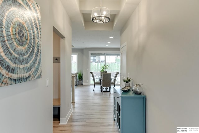 corridor with a chandelier and light hardwood / wood-style flooring