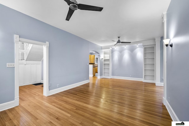 unfurnished living room with ceiling fan, built in features, and light wood-type flooring