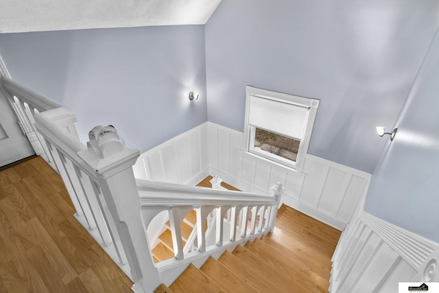 stairway with hardwood / wood-style floors and lofted ceiling