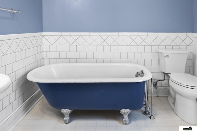 bathroom featuring toilet, a tub, and tile walls