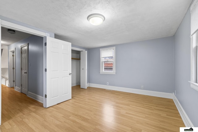 unfurnished bedroom with a textured ceiling and light hardwood / wood-style flooring