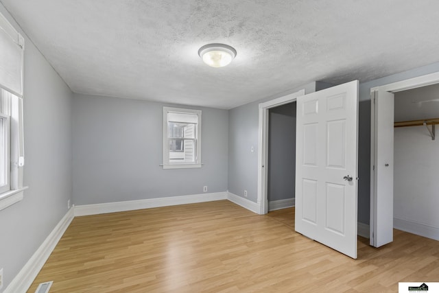 unfurnished bedroom with a closet, light hardwood / wood-style floors, and a textured ceiling