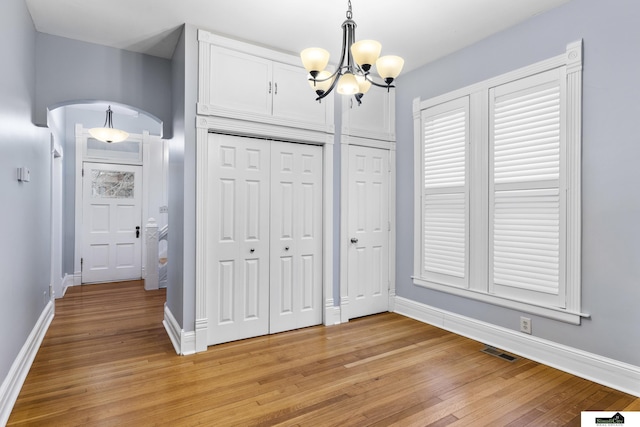 unfurnished bedroom featuring a chandelier and light hardwood / wood-style flooring