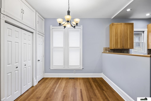 unfurnished dining area featuring hardwood / wood-style floors and an inviting chandelier