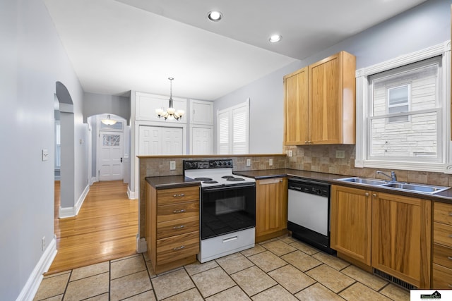 kitchen featuring sink, tasteful backsplash, a notable chandelier, pendant lighting, and white appliances