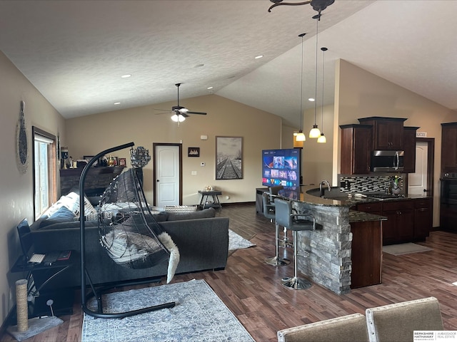 living room featuring a textured ceiling, ceiling fan, dark wood-type flooring, and lofted ceiling