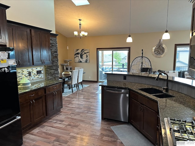 kitchen with black refrigerator, pendant lighting, stainless steel dishwasher, and wood-type flooring