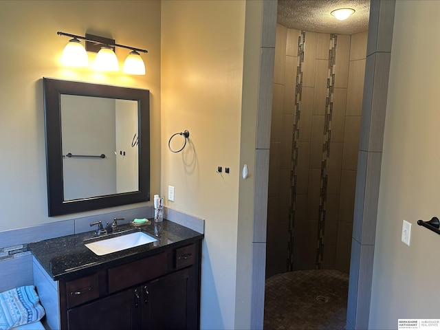 bathroom featuring a tile shower, vanity, and a textured ceiling