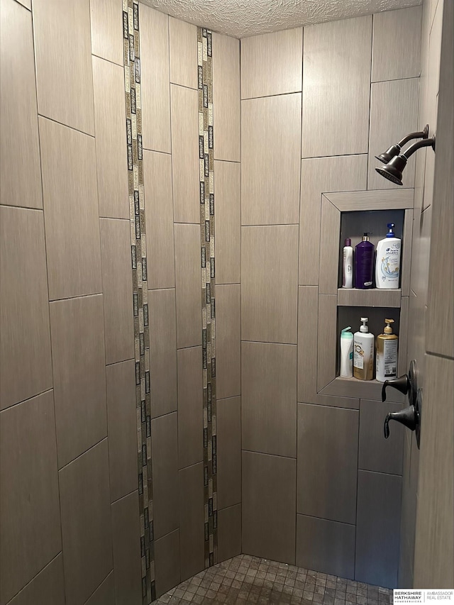 bathroom with a tile shower and a textured ceiling