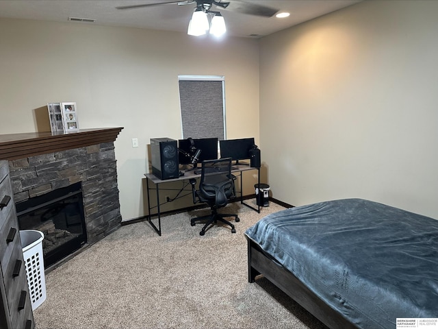 carpeted bedroom featuring ceiling fan and a fireplace