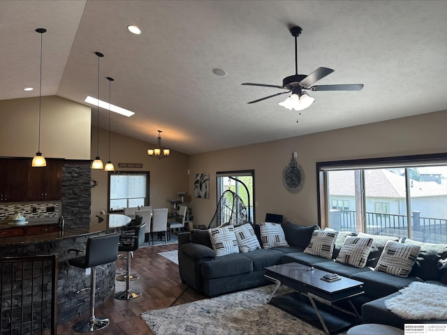 living room with ceiling fan with notable chandelier, dark hardwood / wood-style flooring, and vaulted ceiling