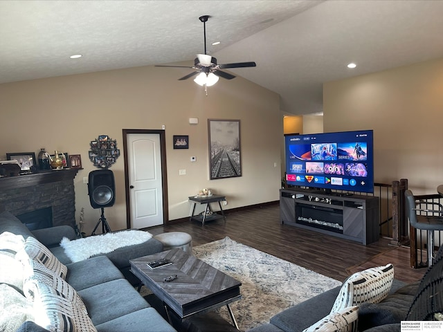 living room featuring ceiling fan, dark hardwood / wood-style floors, a textured ceiling, lofted ceiling, and a fireplace