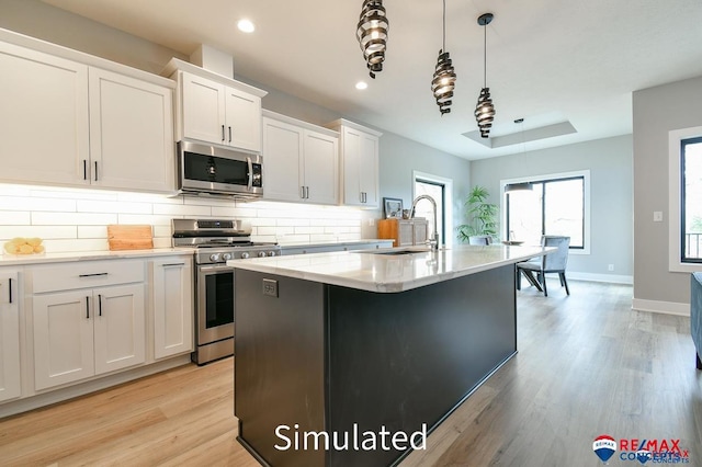 kitchen featuring pendant lighting, sink, an island with sink, appliances with stainless steel finishes, and white cabinetry