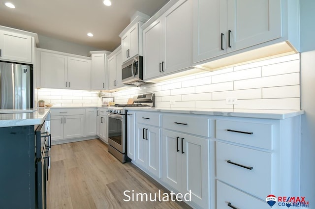 kitchen featuring decorative backsplash, white cabinetry, light hardwood / wood-style floors, and appliances with stainless steel finishes