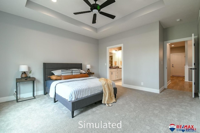 carpeted bedroom featuring ceiling fan, connected bathroom, and a tray ceiling