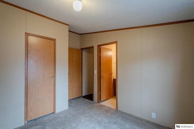 unfurnished bedroom with a closet, light carpet, crown molding, and a textured ceiling