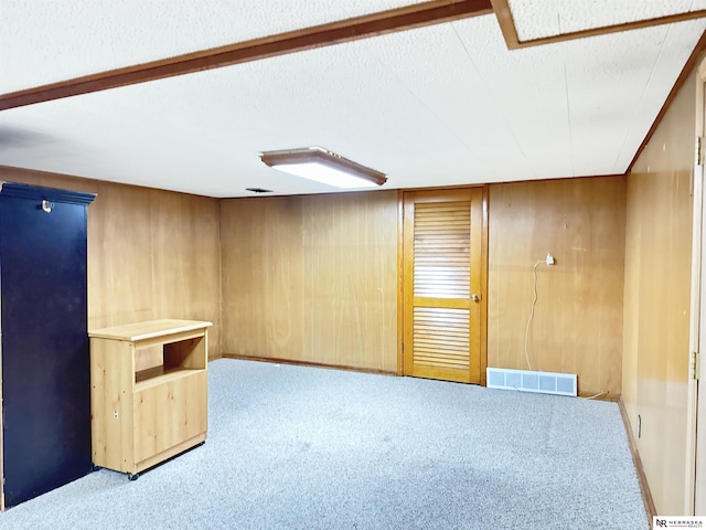 carpeted spare room featuring wooden walls and a textured ceiling