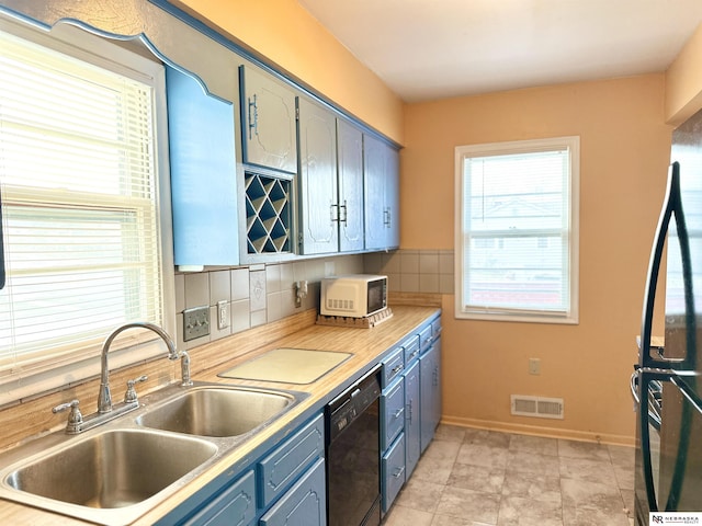 kitchen featuring decorative backsplash, refrigerator, sink, light tile patterned floors, and black dishwasher