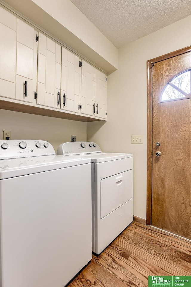 laundry area featuring washer and dryer, a textured ceiling, light hardwood / wood-style flooring, and cabinets