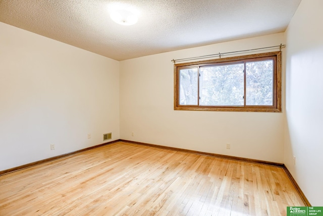 spare room with light hardwood / wood-style flooring and a textured ceiling