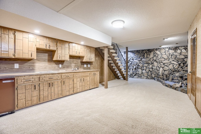 basement with a textured ceiling, sink, and light carpet