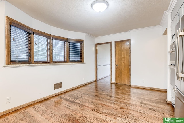 unfurnished bedroom featuring ornamental molding, a textured ceiling, and light hardwood / wood-style flooring