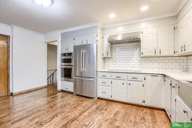 kitchen with white cabinetry, stainless steel appliances, tasteful backsplash, light hardwood / wood-style flooring, and exhaust hood