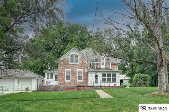 view of front of property featuring a garage, a balcony, an outbuilding, and a front lawn