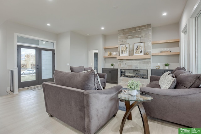 living room featuring a stone fireplace, french doors, and light hardwood / wood-style floors