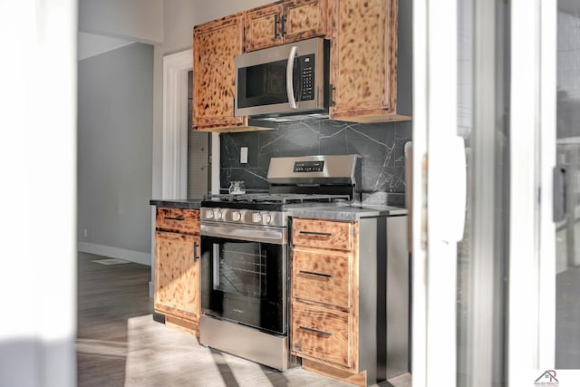 kitchen with backsplash, stainless steel appliances, and light hardwood / wood-style flooring